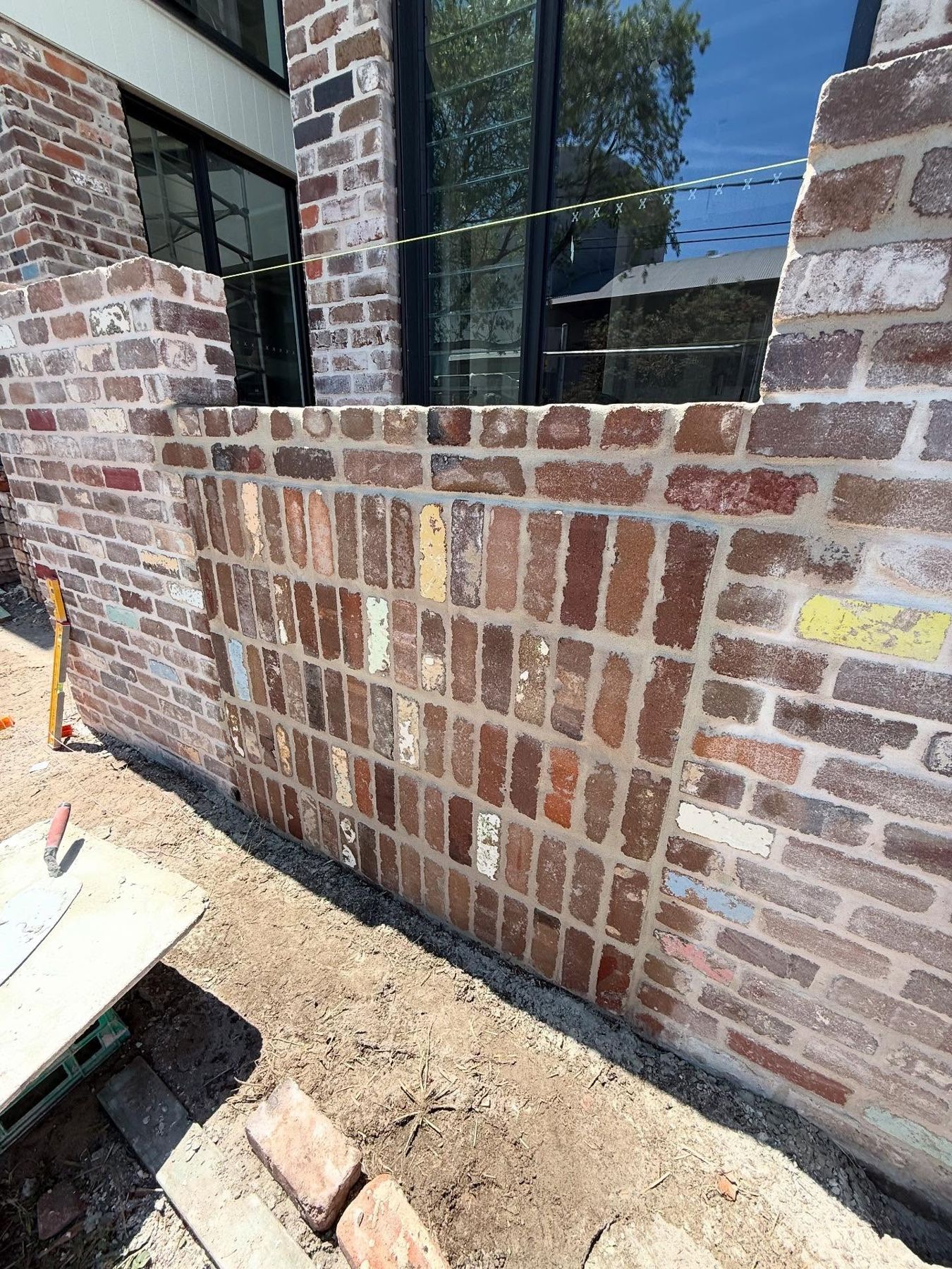 Recycled-brick fence with a soldier-course cap running along a new home