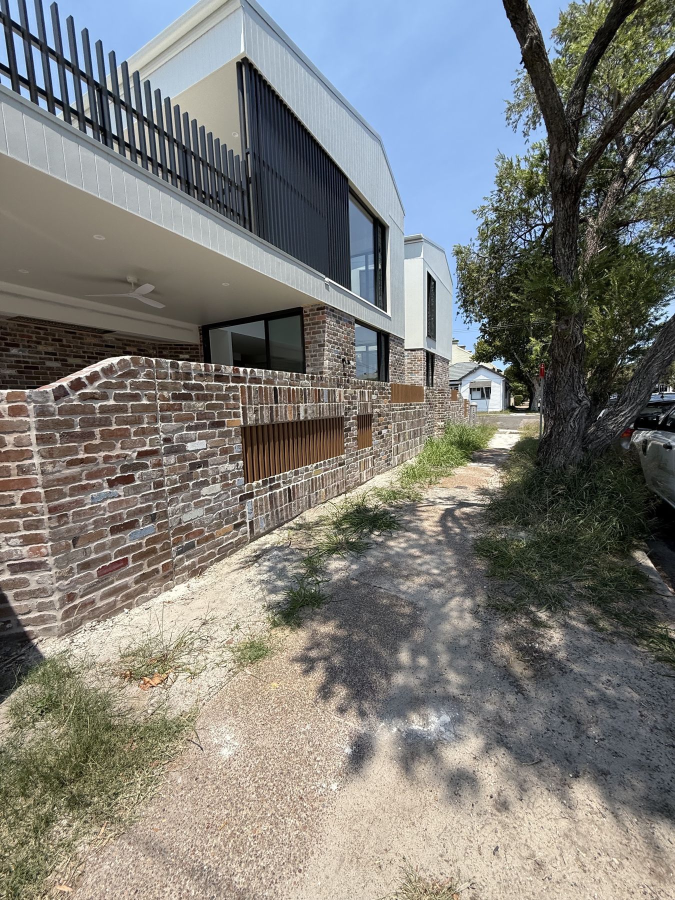 Finished recycled-brick front fence with timber battens in front of a modern two-storey home